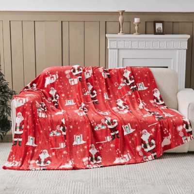 Red Christmas-themed blanket with Santa Claus on a couch in a living room.