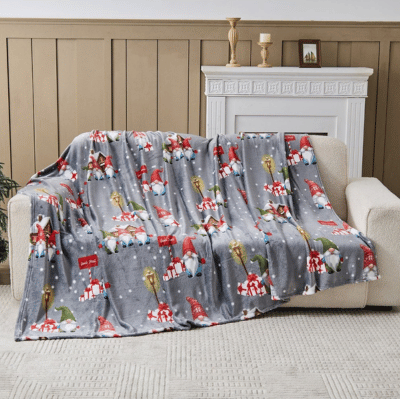 Gray blanket with Christmas-themed design draped over a sofa in a living room.
