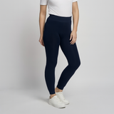 A model wearing PINNS cosy black fleece lined leggings, paired with a white t-shirt and white sneakers, standing against a light gray studio background. Available to buy from Mooreheads Bessbrook 