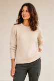 A woman wearing an Emreco ivory bubble textured crewneck sweater and dark olive cargo pants, standing against a neutral beige background.